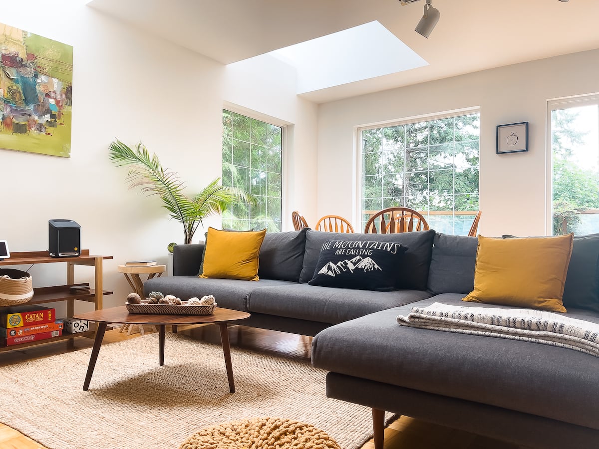 Open living room with mid-century furnishings and forest-facing windows